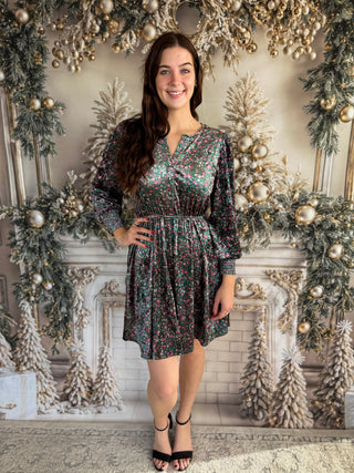 Woman in a floral dress standing in front of a decorated Christmas fireplace.
