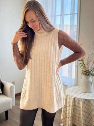 Woman wearing a beige sleeveless sweater in a home setting