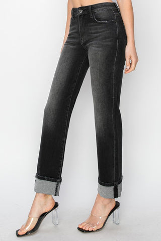 Person wearing black jeans with rolled-up cuffs on a white background