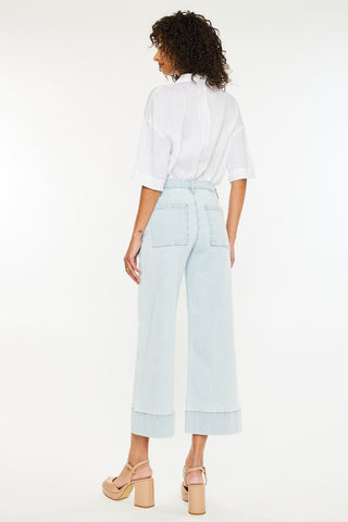 Lady standing wearing crop length wide leg pants, rear view. 