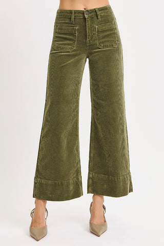 Green corduroy pants worn by a person on a white background
