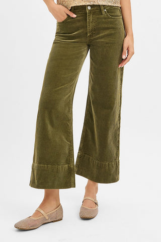 Green velvet wide-leg pants worn by a person on a white background