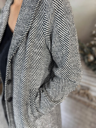 Close-up of a person wearing a black and white herringbone patterned coat.