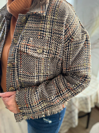Plaid jacket with button details worn by a person, blurred background