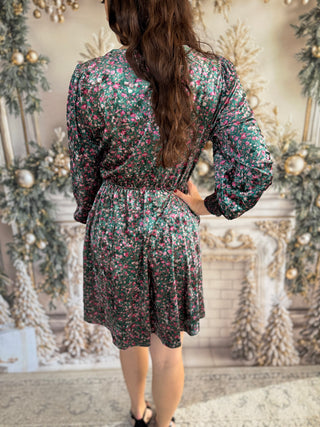 Person wearing a floral dress in a decorated room with Christmas trees.