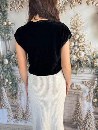 Person wearing a black top and white skirt in front of decorative Christmas trees.
