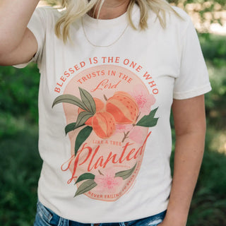 Person wearing a white t-shirt with a graphic design and text outdoors.