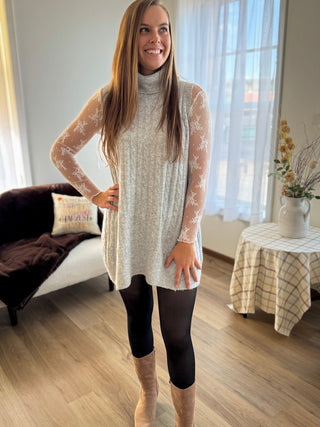 Woman wearing a long, light-colored lace dress in a living room.