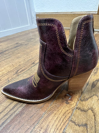Pair of purple ankle boots with gold accents on a wooden floor.