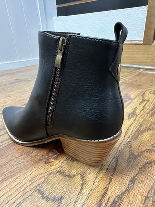 Black ankle boot with a zipper on a wooden floor