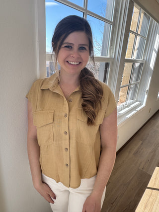 Photo of a woman in a tan button up top with two front pockets.