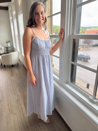 Woman wearing a striped dress standing by a window