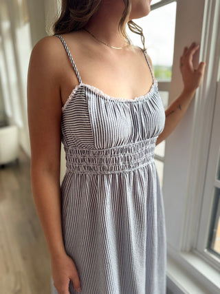 Woman wearing a striped dress standing by a window
