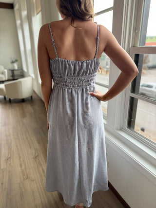 Woman wearing a striped dress standing by a window indoors