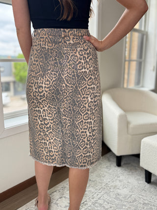 Photo of a woman standing in front of a window wearing a cheetah print skirt.