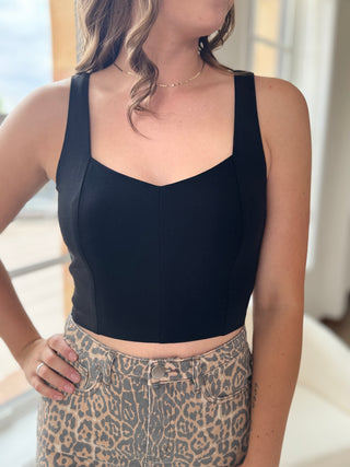 Person wearing a black tank top and leopard print pants indoors