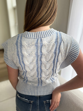 Person wearing a blue and white patterned sleeveless sweater