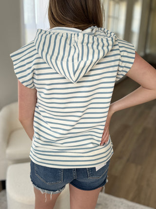 Person wearing a striped hoodie and denim shorts in an indoor setting