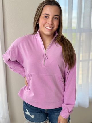 Woman wearing a pink pullover with a zipper, standing indoors.
