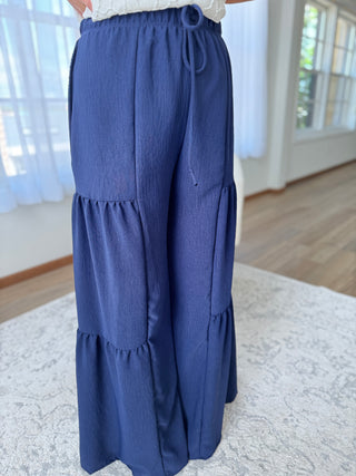 Blue tiered pants worn by a person indoors on a light-colored rug.