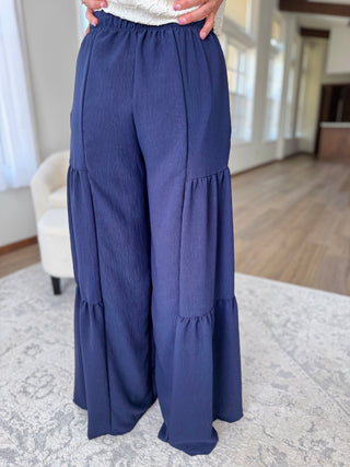 Navy blue tiered pants worn by a person indoors.