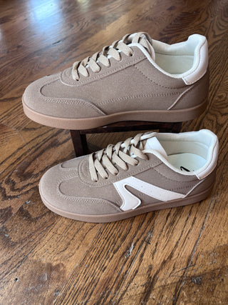 Pair of beige sneakers with white accents on a wooden floor