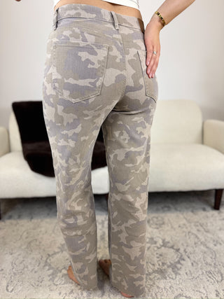A person shown from the back wearing straight-leg jeans with a light gray and beige camouflage pattern, standing in a living room setting.
