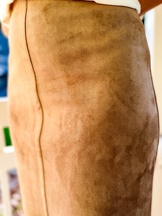 Close-up of a tan suede skirt with a visible center seam, worn by a model.