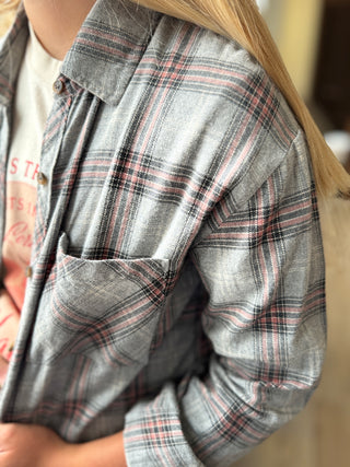 Close-up of a person wearing a gray plaid shirt with a blurred background