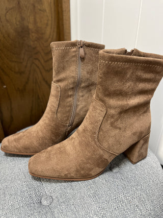 Pair of brown suede ankle boots on a textured surface with a neutral background