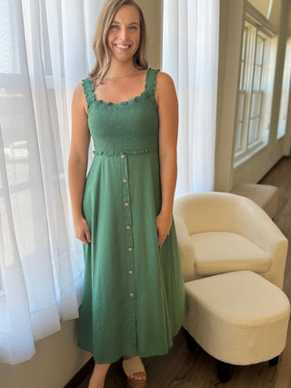 Photo of a woman wearing a green dress with buttons down the front and a smocked top.