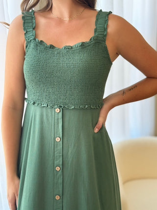 Green dress with button details worn by a person, against a neutral background