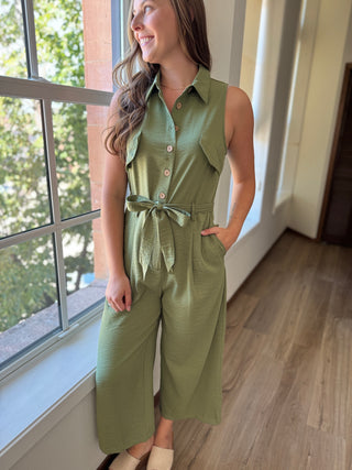 Photo of a woman wearing a green jumpsuit with buttons going up the front and a collar.