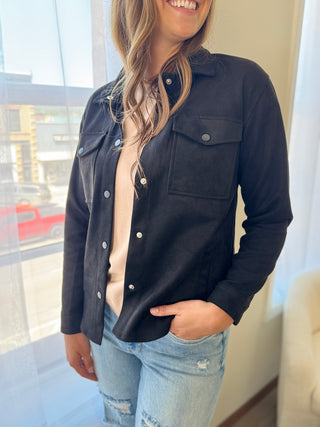 Woman wearing a black denim jacket with a blurred cityscape background