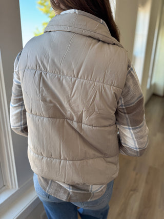 Person wearing a beige quilted jacket indoors