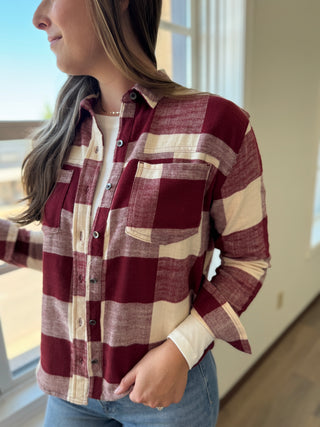 Person wearing a maroon and beige checkered shirt indoors