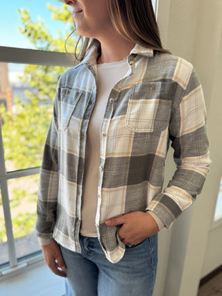 Person wearing a plaid shirt and jeans indoors with a window in the background