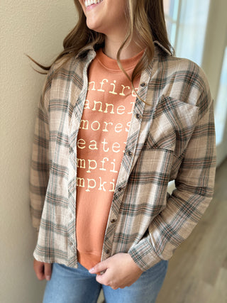 Person wearing a plaid shirt over a graphic t-shirt with text.