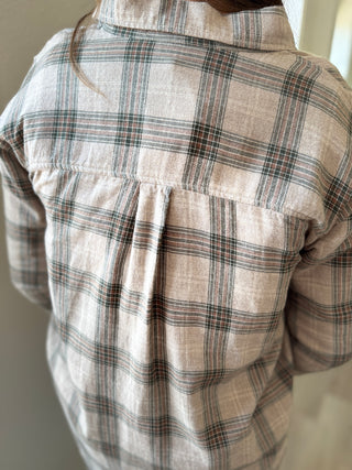 Plaid shirt with a focus on the collar and chest area against a neutral background