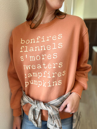 Person wearing a brown sweatshirt with autumn-themed text against a neutral background