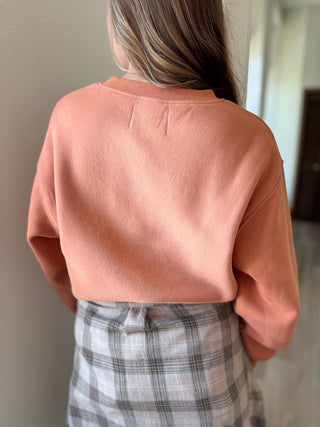Person wearing a pink sweater and plaid skirt in an indoor setting