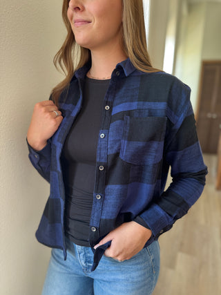 Woman wearing a blue and black plaid shirt with a plain background