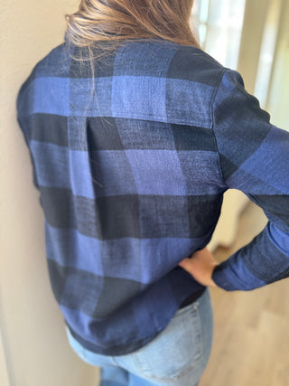 Person wearing a blue and black plaid shirt with a neutral background