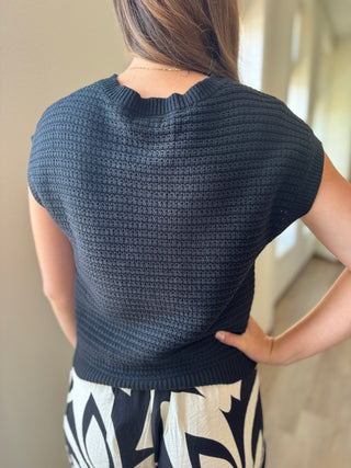 Person wearing a dark blue knitted top with a neutral background