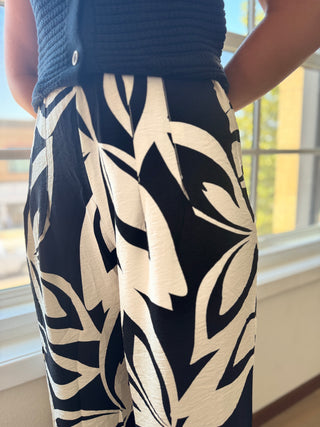 Person wearing navy pants with a white abstract pattern, standing indoors.