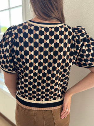 Person wearing a patterned sweater with a neutral background