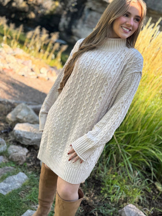 Woman in an oatmeal cable knit mock neck sweater dress with tall boots | V-Rae's Boutique