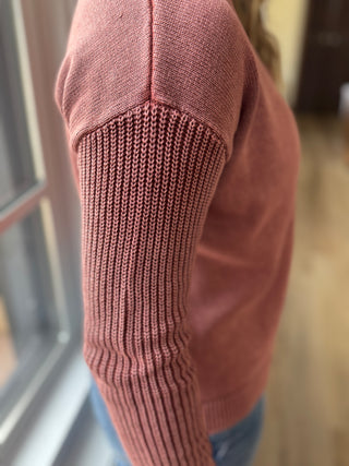 Close-up of a pink knitted sleeve with a blurred background