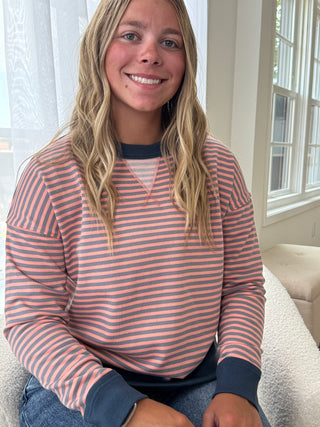 Person wearing a pink and blue striped shirt sitting on a couch.