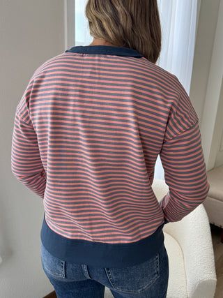 Person wearing a striped shirt and jeans sitting on a couch.